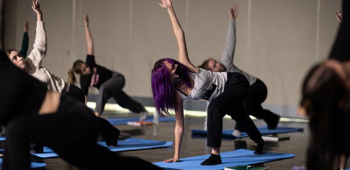 Students lean over, stretching one arm in the air during a yoga exercise.